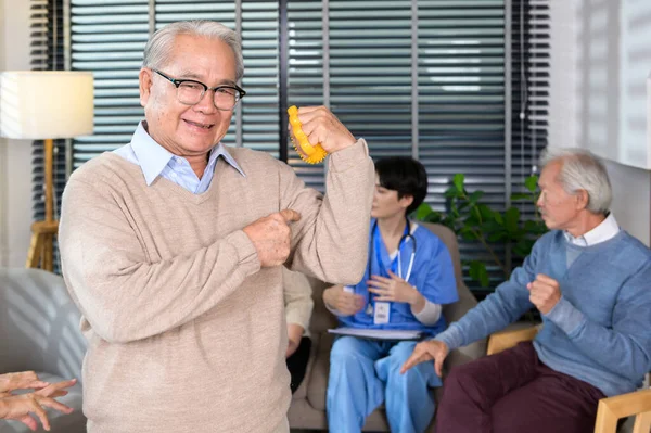 Portrait of asian elderly man doing hand exercise with hand stress ball at senior healthcare center.