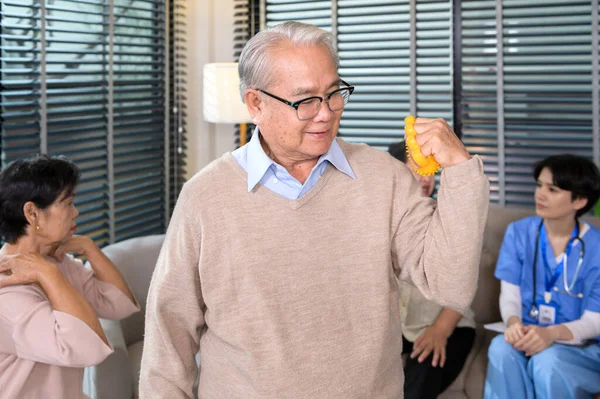 Portrait of asian elderly man doing hand exercise with hand stress ball at senior healthcare center.