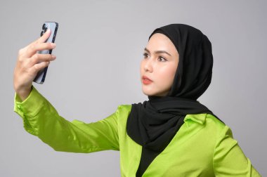 A Beautiful musllim woman with hijab using smartphone over white background, technology concept. 		