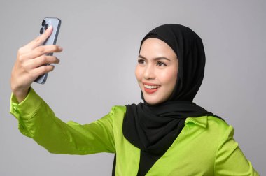 A Beautiful musllim woman with hijab using smartphone over white background, technology concept. 		