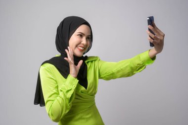 A Beautiful musllim woman with hijab using smartphone over white background, technology concept. 		
