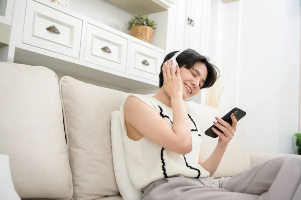 stock image An Asian teenager wearing headphones enjoying music at home 