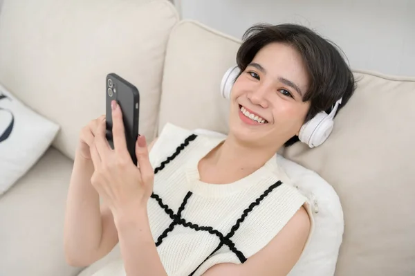 一个带着耳机在家里欣赏音乐的亚洲少年 — 图库照片