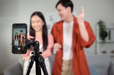 Asyalı genç çiftler akıllı telefonla video dansı yapıyor, sosyal medyada video içeriğini paylaşıyorlar.. 