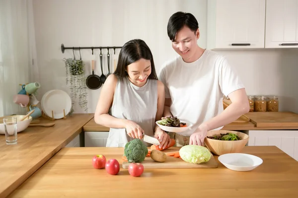 An Asian young couple enjoy cooking with healthy vegetables and fruits ingredients in kitchen at home , healthy wellness lifestyle concept.