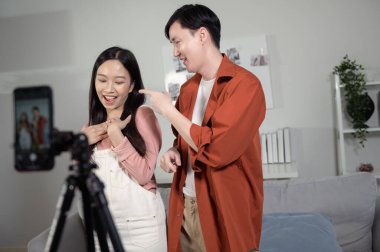 Asyalı genç çiftler akıllı telefonla video dansı yapıyor, sosyal medyada video içeriğini paylaşıyorlar.. 