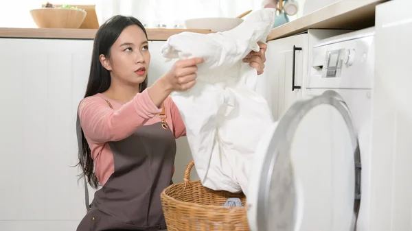 Exhausted  Asian young woman with dirty clothes , doing laundry in home
