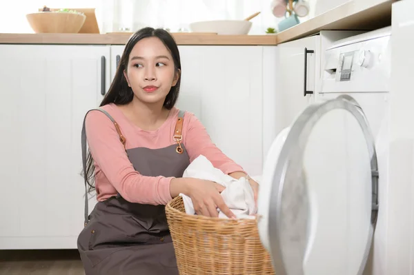 Exhausted  Asian young woman with dirty clothes , doing laundry in home