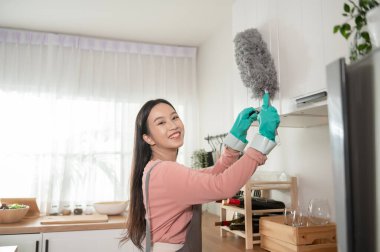 Mutlu Asyalı genç kadın kanepe ve mobilyaları temizliyor, sağlıklı yaşam tarzı konsepti