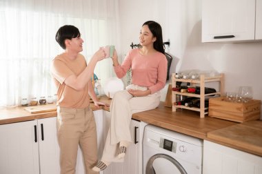 Mutlu genç Asyalı çift sabahları mutfakta kahve içip rahatlıyor.