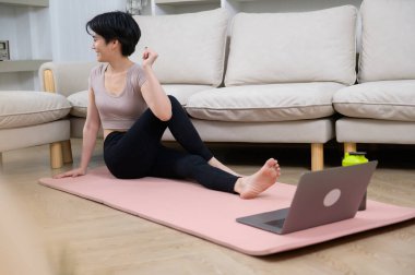 Asyalı genç bir kadın spor yapıyor, spor yapıyor, evde egzersiz yapıyor, sağlıklı yaşam tarzı kavramı var.