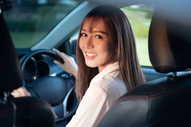 Genç Asyalı güzel bir kadın emniyet kemeri takılı bir araba kullanıyor.