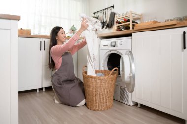 Mutlu Asyalı genç kadın evde çamaşır yıkıyor, sağlıklı yaşam tarzı konsepti.