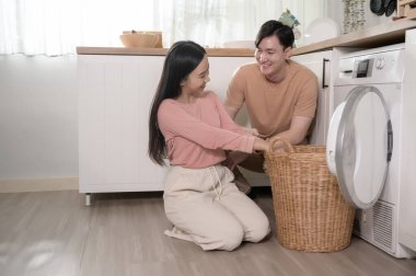 Happy Asian young couple doing laundry together at home , healthy lifestyle concept 