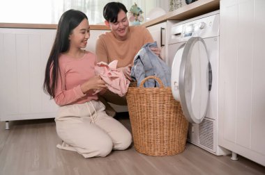 Happy Asian young couple doing laundry together at home , healthy lifestyle concept 