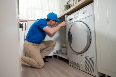An Asian young Technician service man wearing blue uniform checking electrical appliances in home