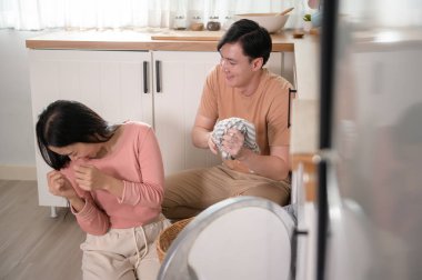 Happy Asian young couple doing laundry together at home , healthy lifestyle concept 