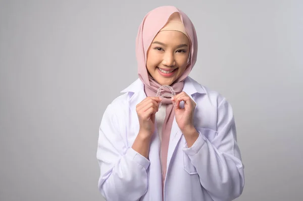 白い背景スタジオ 歯科医療 整形外科のコンセプトに沿ってブレースを保持する若いイスラム教徒の女性歯科医 — ストック写真
