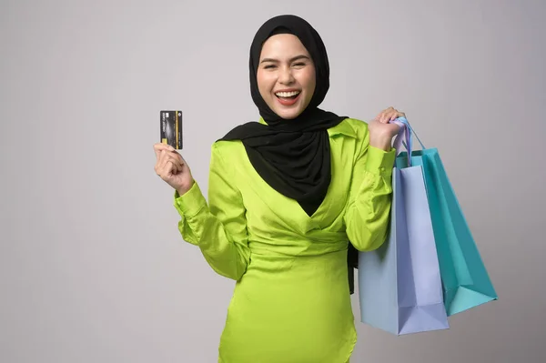 一个漂亮的穆斯林女人 头戴头巾 头戴信用卡 头戴购物袋 头戴白色背景工作室 购物和金融概念 — 图库照片
