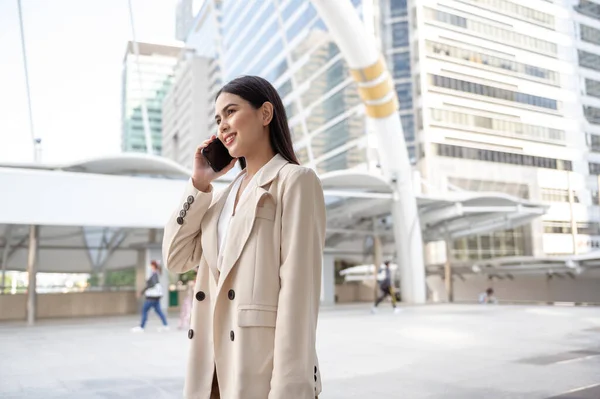 Modern şehirde akıllı telefon kullanan güzel bir iş kadınının portresi.