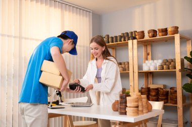 Kafkasyalı genç kadın karton kutusunu dükkanındaki teslimatçıdan aldı.