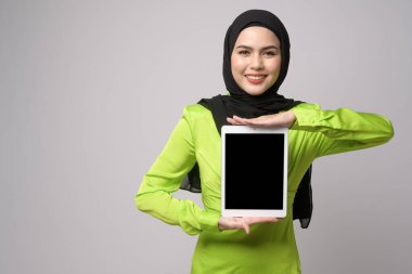 A Beautiful musllim woman with hijab using tablet over white background, technology concept. 	