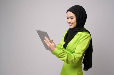 A Beautiful musllim woman with hijab using tablet over white background, technology concept. 	