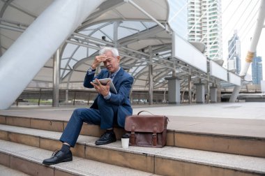 Asyalı olgun orta yaşlı işadamı modern şehirde endişeli ve hayal kırıklığına uğramış hissediyor