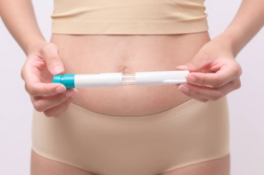 Close up woman using IVF treatment injection on belly to prepare reproductive fertility , Ovulation stimulation .	