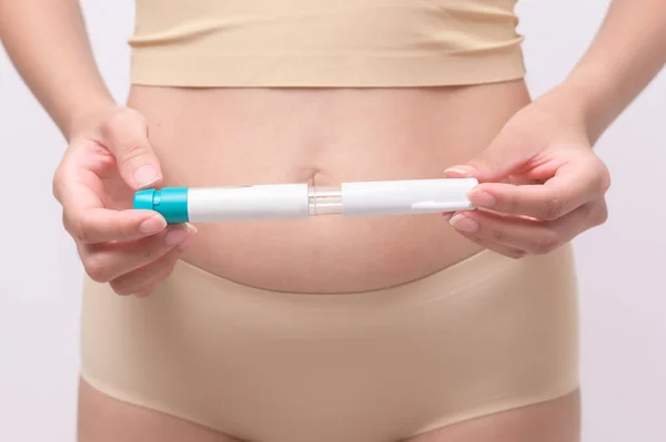 Close up woman using IVF treatment injection on belly to prepare reproductive fertility , Ovulation stimulation .