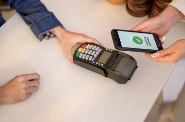 Kadın müşteri QR kod ödemesini akıllı telefondan dükkanda ödeme yapmak için kullanıyor. 