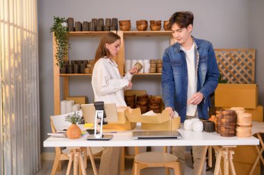 Genç bir çift, dükkânda müşterilere satış yapan el işi ürünlerini kontrol edip paketliyor.