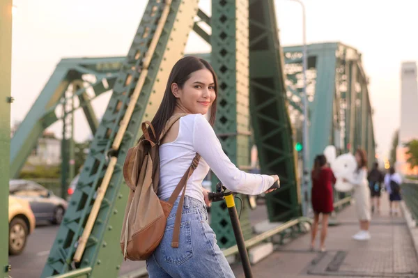 stock image Portrait of young beautiful woman with an electric scooter  over bridge in modern city  background