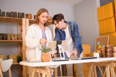 Genç bir çift, dükkânda müşterilere satış yapan el işi ürünlerini kontrol edip paketliyor.