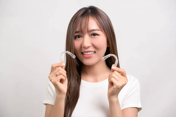 白い背景スタジオ 歯科医療 整形外科のコンセプトに沿ってブレースを保持している若い笑顔の女性 — ストック写真