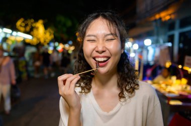 Güzel Asyalı genç bir turist gece Khao San Yolu 'nu geziyor ve geziyor. Bangkok, Tayland, Tatil ve seyahat konsepti.