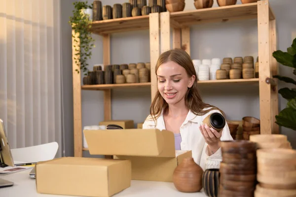 若いかなり女性起業家チェックと彼女の店で顧客に販売クラフト製品を包装 — ストック写真