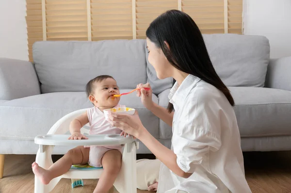 stock image A Young mother helping baby eating blend food on baby chair