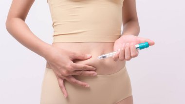 Close up woman using IVF treatment injection on belly to prepare reproductive fertility , Ovulation stimulation .	