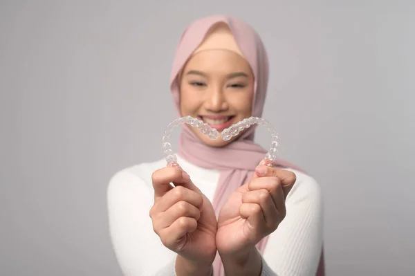 一名年轻微笑的穆斯林妇女 头戴头巾 手持无创矫正器 在工作室 牙齿保健和牙齿矫正的概念 — 图库照片