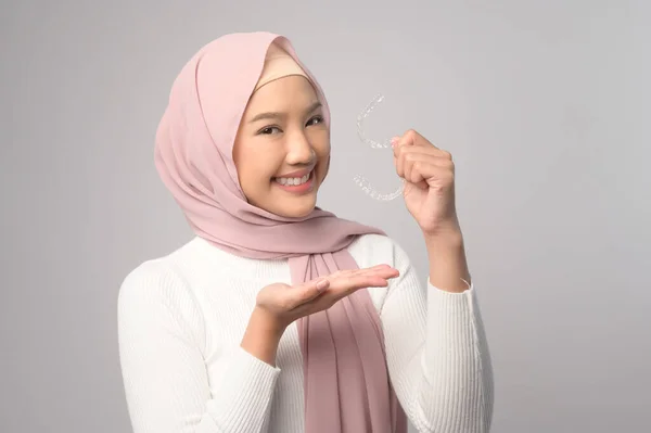 若いです笑みを浮かべてイスラム教徒の女性とともにスタジオでInvisalineブレースを保持しています 歯科医療と整形外科の概念 — ストック写真