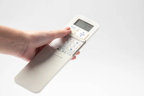 Holding air conditioner remote control over white background