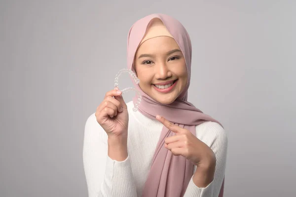 若いです笑みを浮かべてイスラム教徒の女性とともにスタジオでInvisalineブレースを保持しています 歯科医療と整形外科の概念 — ストック写真