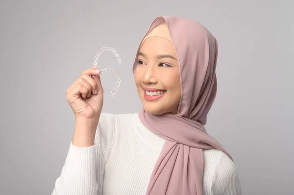 一名年轻微笑的穆斯林妇女 头戴头巾 手持无创矫正器 在工作室 牙齿保健和牙齿矫正的概念 — 图库照片
