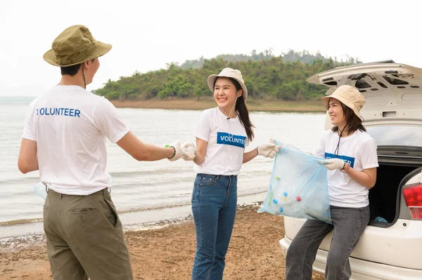 Volunteers from the Asian youth community using rubbish bags cleaning  up nature par