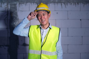 Güvenlik kaskı takan Asyalı Mühendis inşaat alanında çok çalıştığı için yorgun düşmüş.