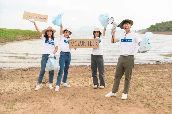 Volunteers from the Asian youth community using rubbish bags cleaning  up nature par