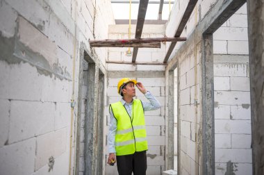 Asyalı bir mühendis kafasına koruyucu kask takıyor. 