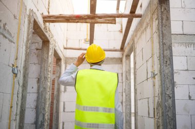 Asyalı bir mühendis kafasına koruyucu kask takıyor. 