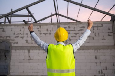 İnşaat alanında güvenlik kaskı takan mutlu Asyalı Mühendis. 